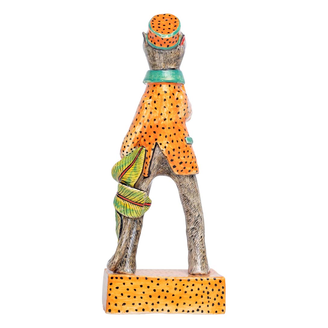 A monkey wearing orange coat & hat showing his thumbs up sculpture