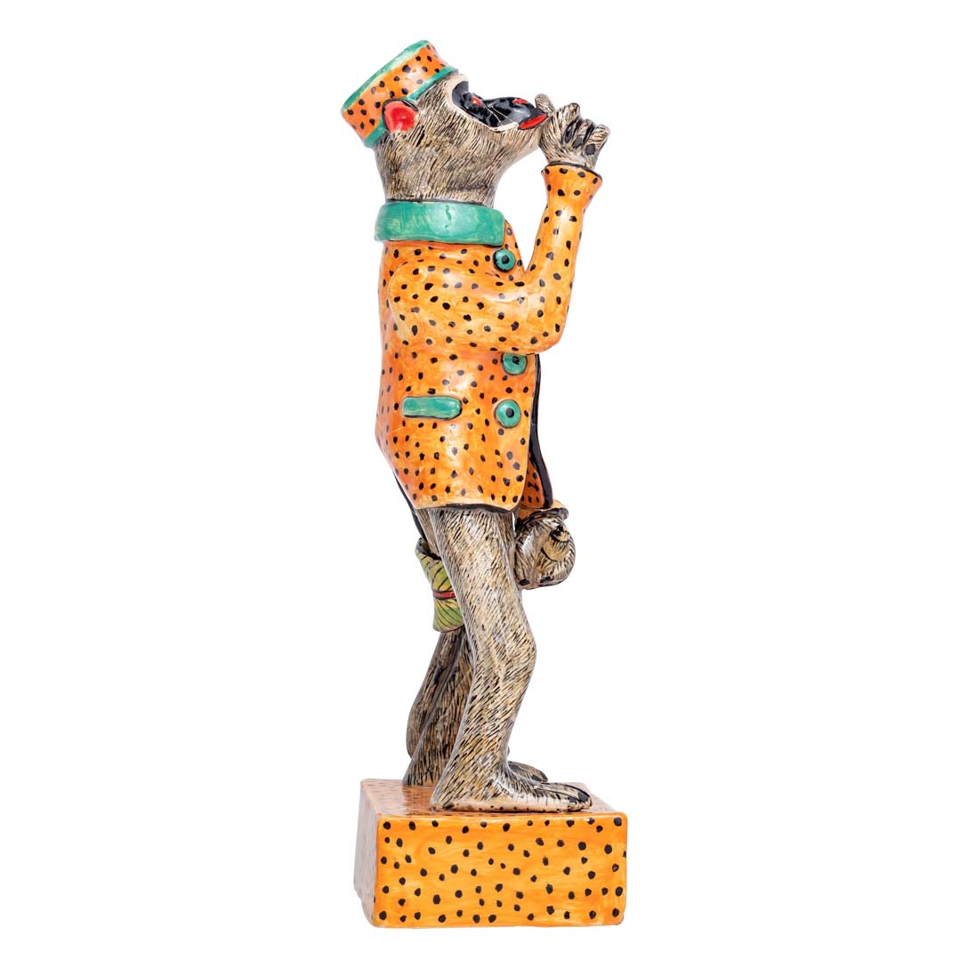 A monkey wearing orange coat & hat showing his thumbs up sculpture