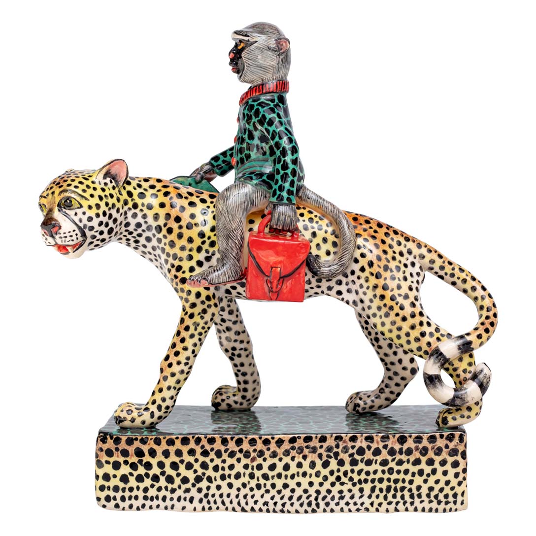 Monkey holding a hand bag riding the leopard sculpture