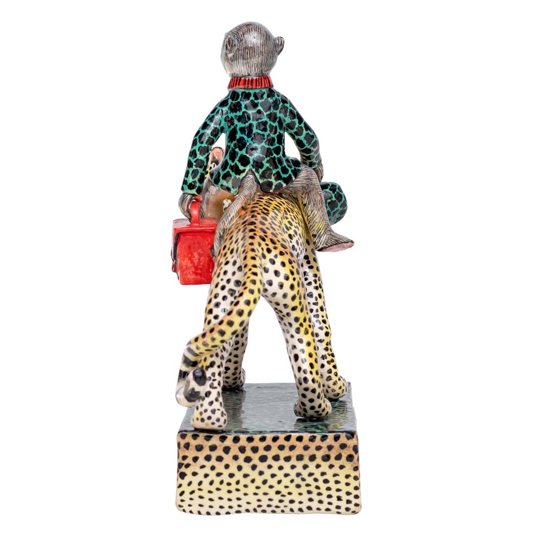 Monkey holding a hand bag riding the leopard sculpture