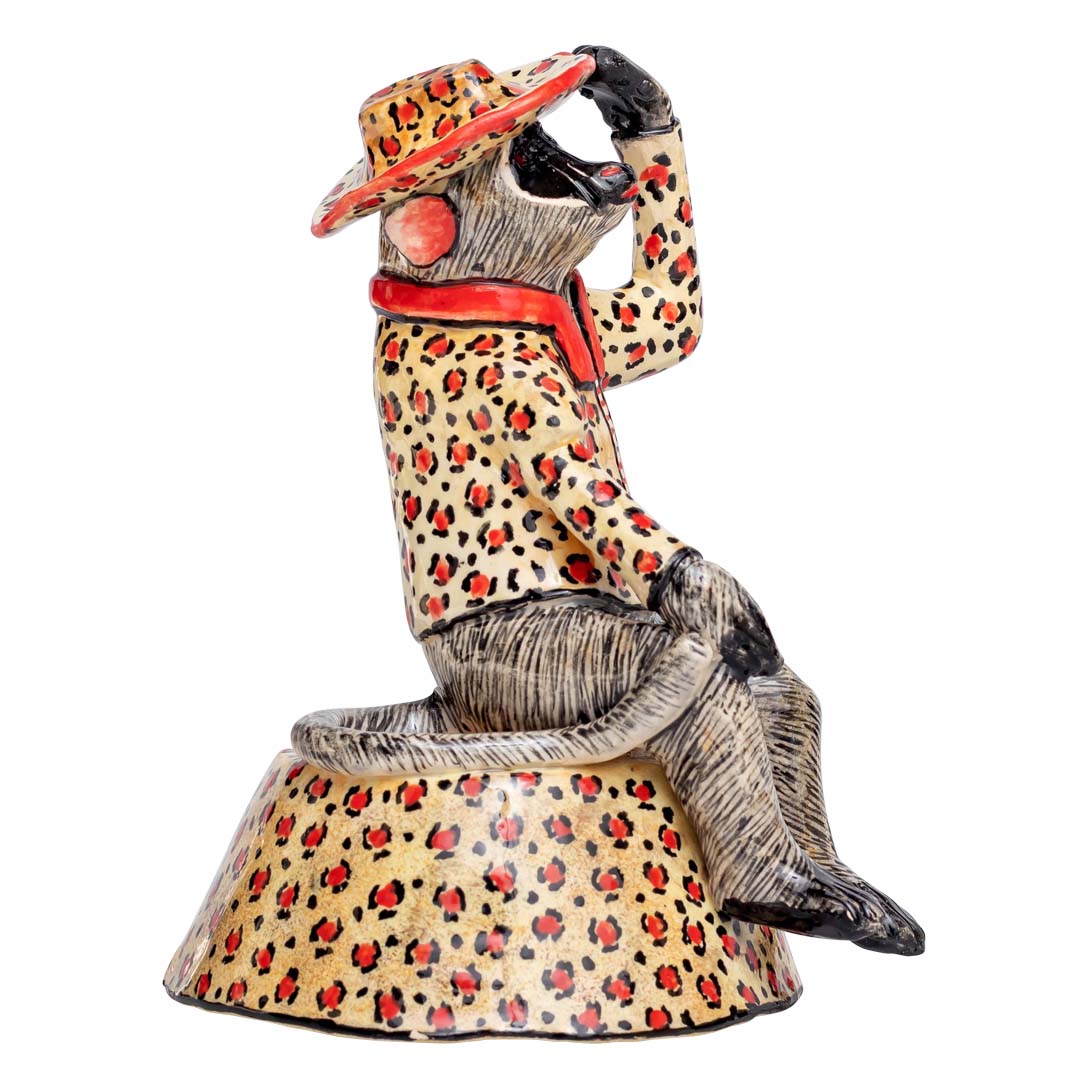 Monkey sitting & wearing a leopard colored coat & hat showing a salute signal sculpture