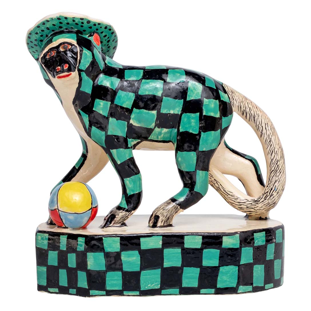 Monkey on a green & black skin design & a hat playing ball sculpture