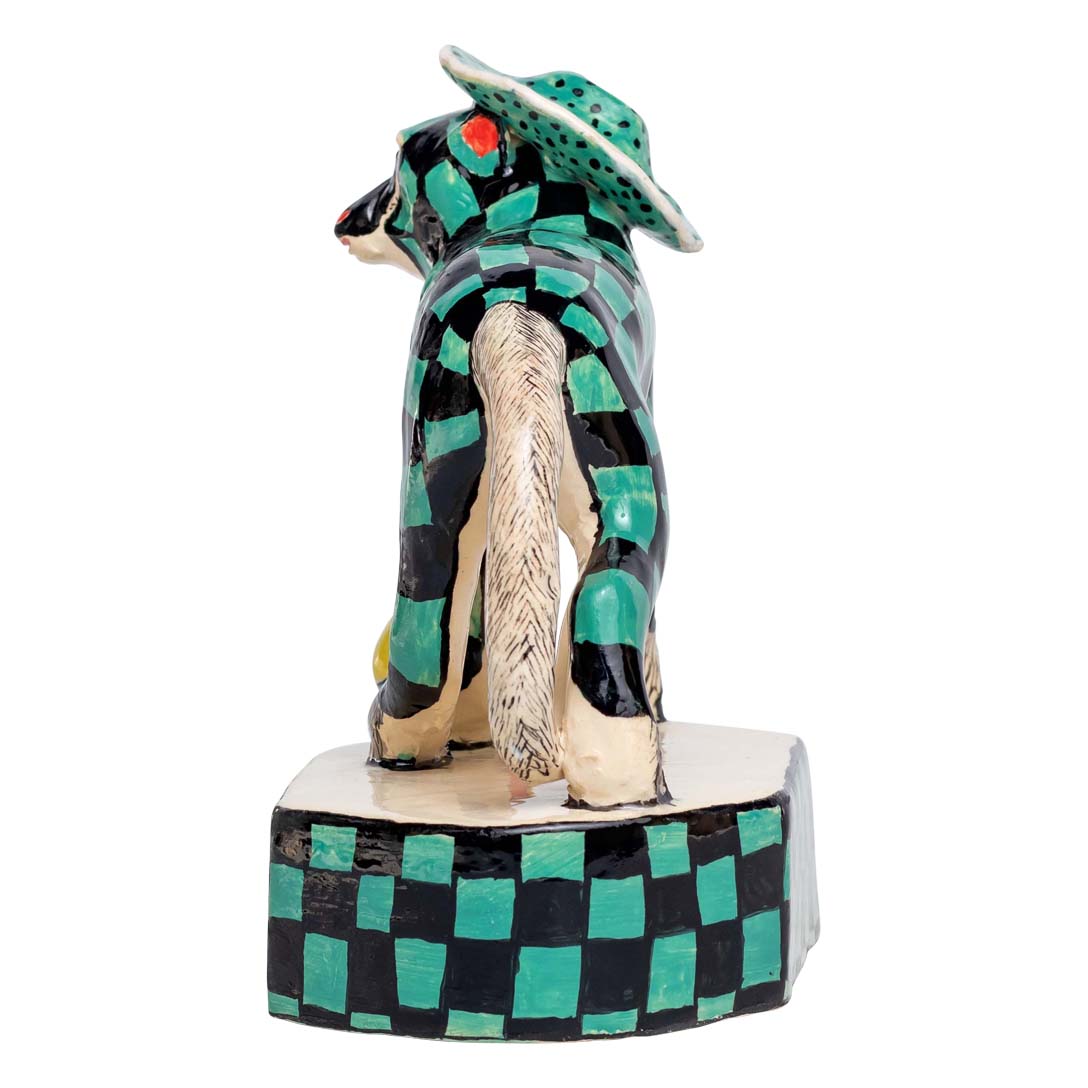 Monkey on a green & black skin design & a hat playing ball sculpture