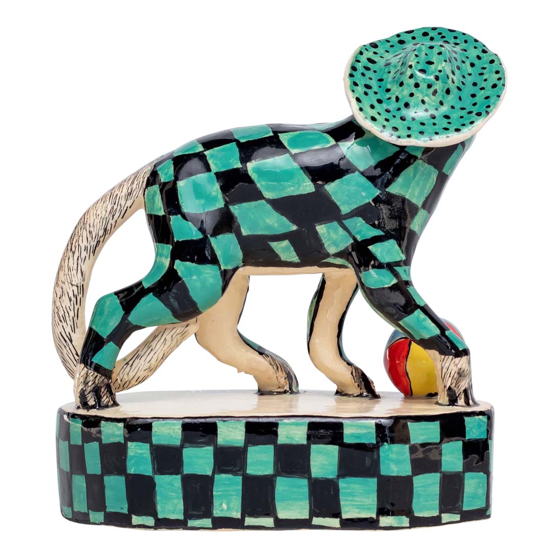 Monkey on a green & black skin design & a hat playing ball sculpture