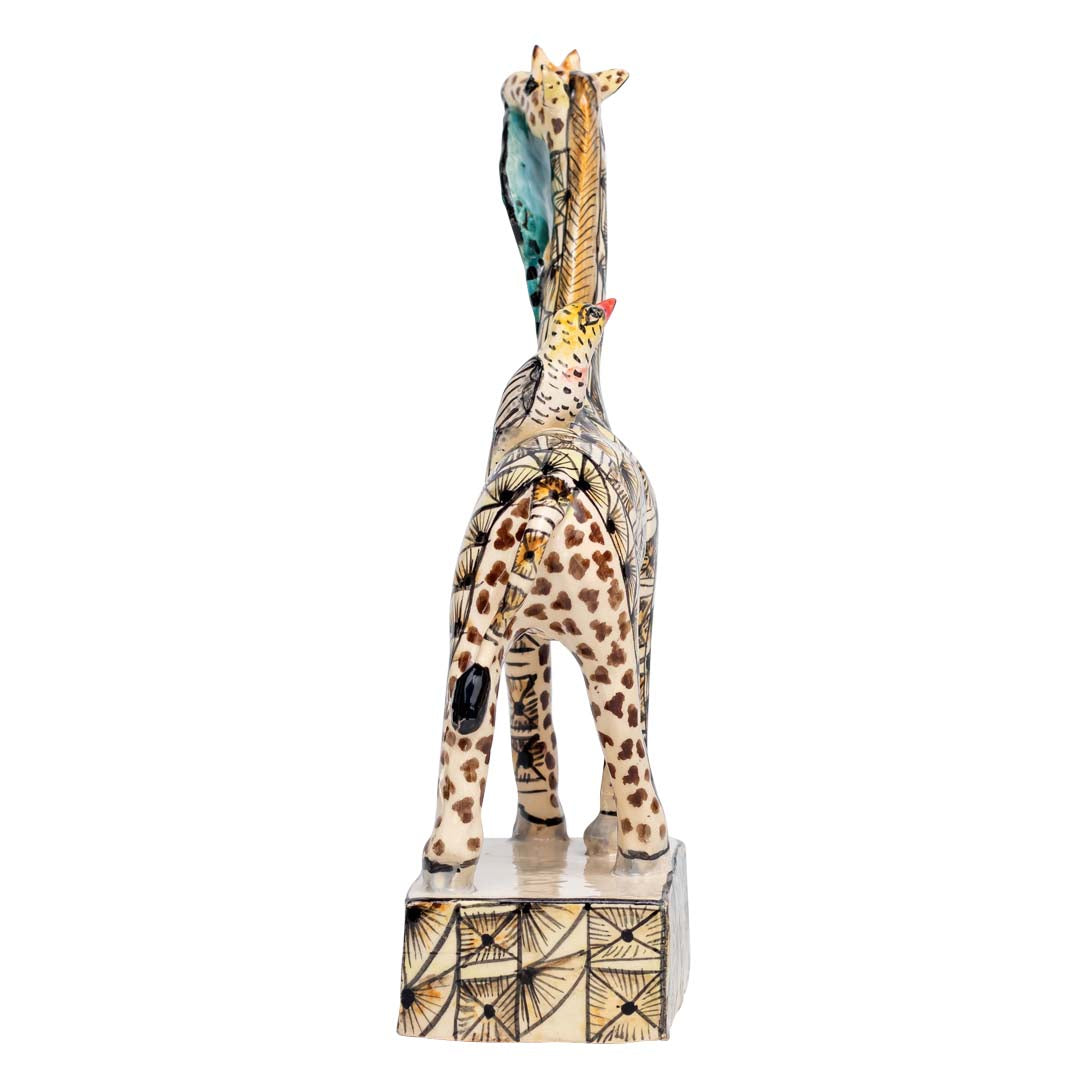 Skin designed giraffe stand eating a leaf while the bird is sitting on its back sculpture